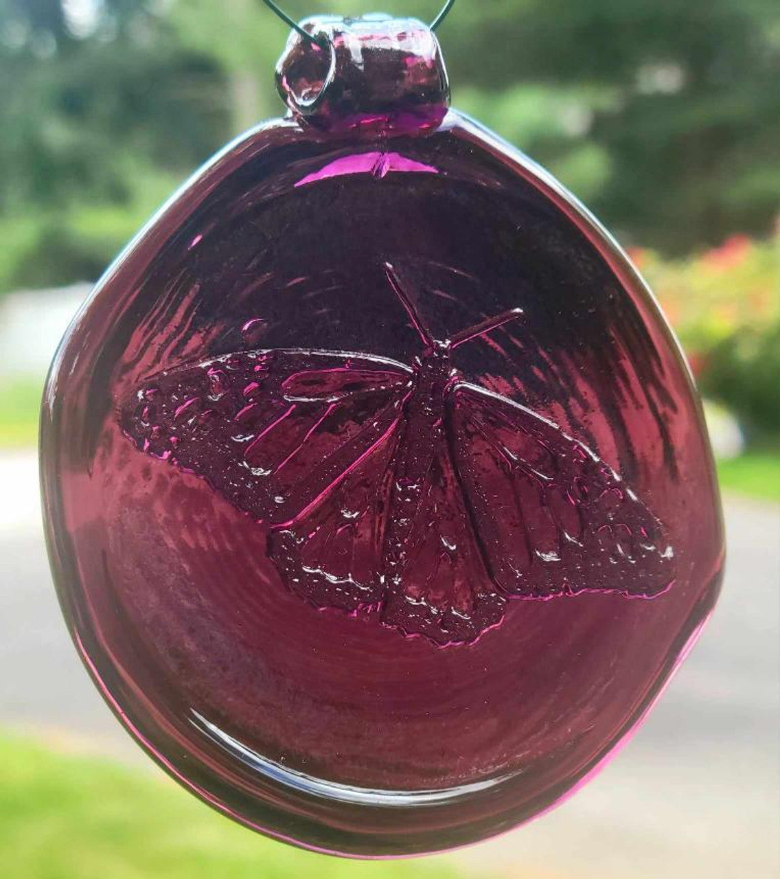 an amethyst purple, round glass suncatcher with a relief image of a butterfly