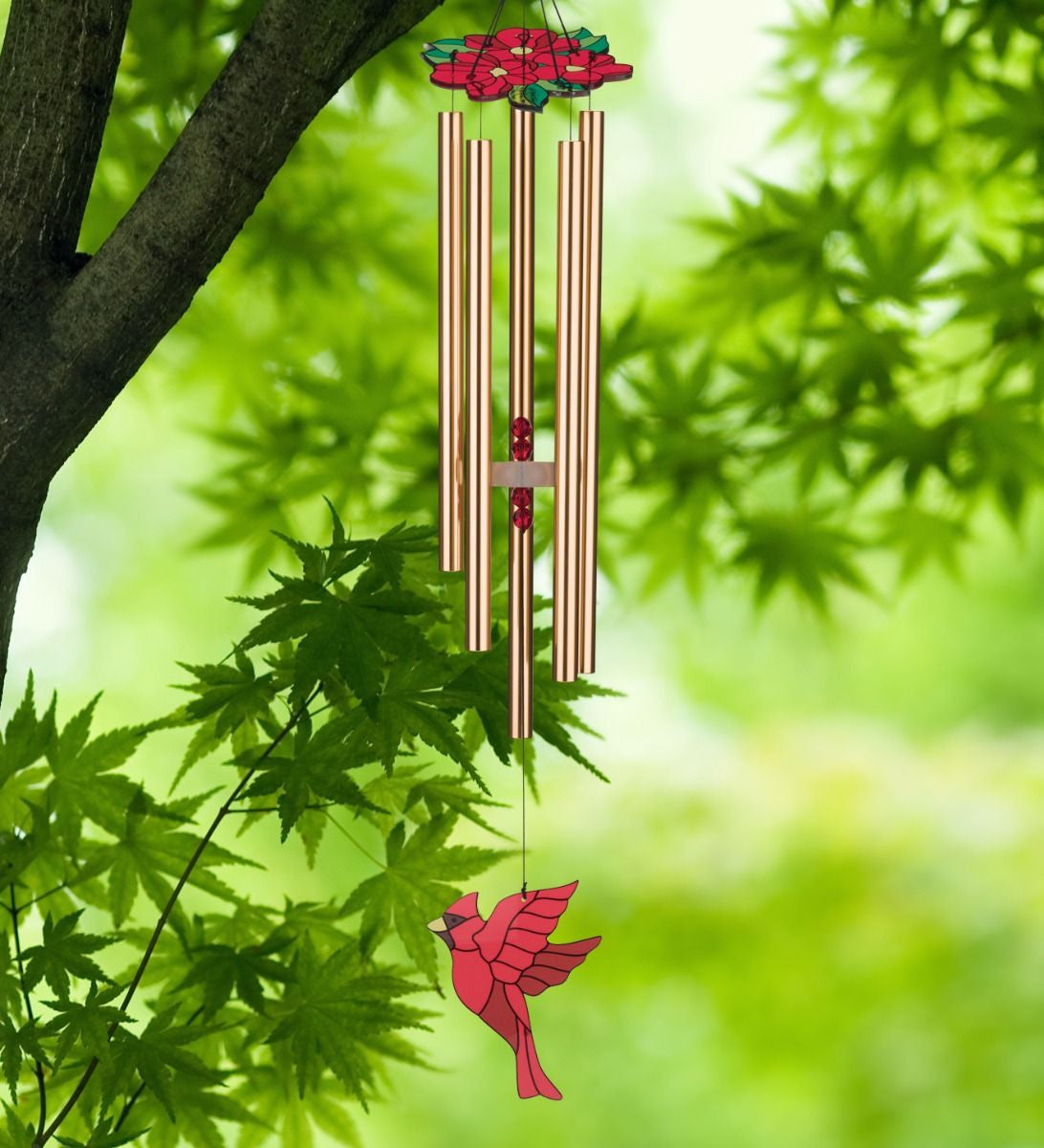 Cardinal Chimes with red floral canopy, copper chime tubes, and stained glass style cardinal sail seen hanging from a tree