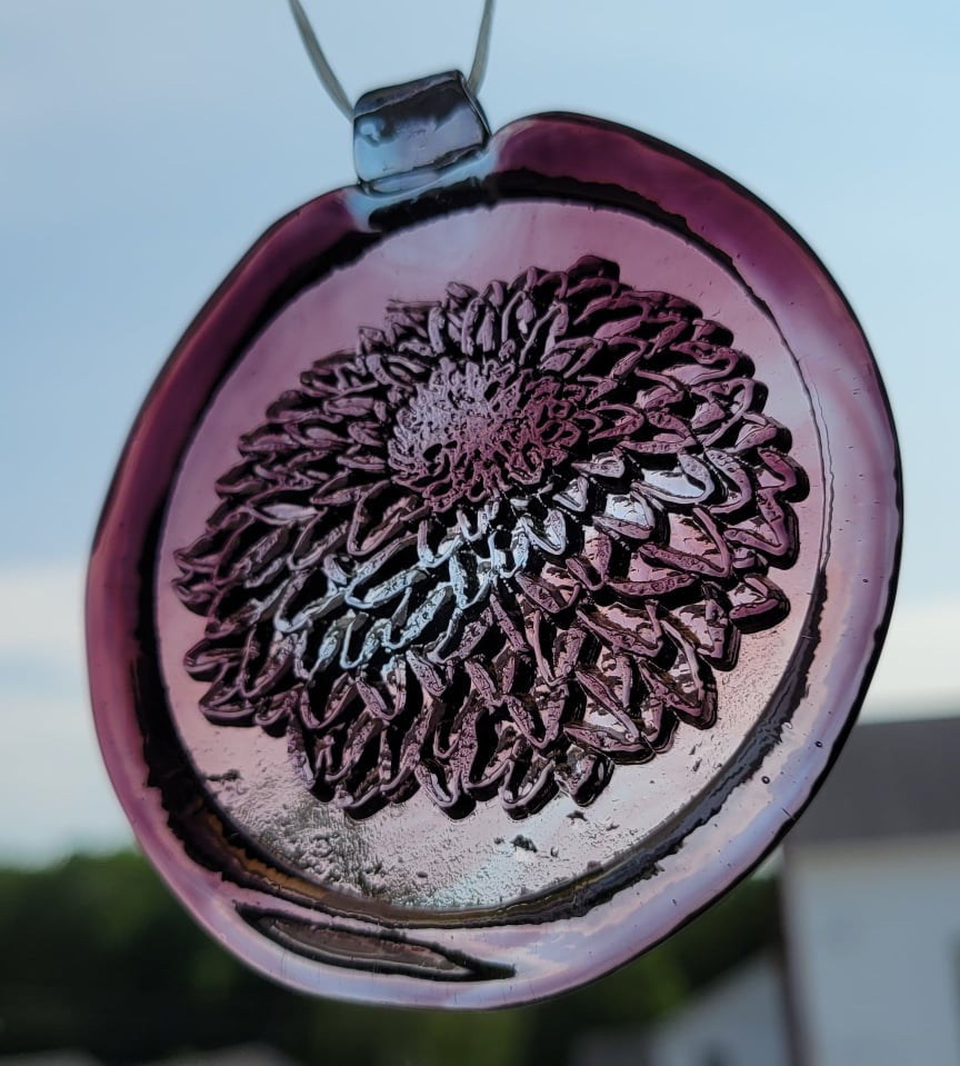 Glass suncatcher with a chrysanthemum flower design shown in light purple to better see the design.