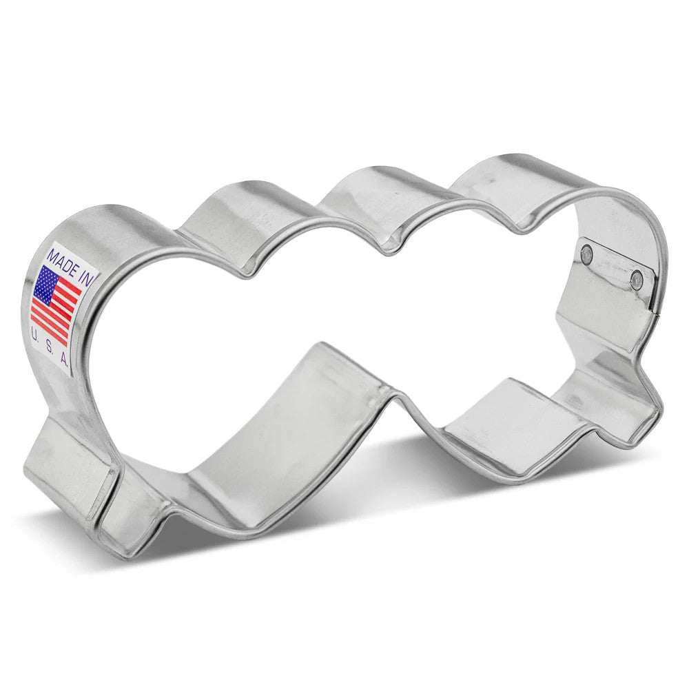 a silver, tin cookie cutter in the shape of folded heart-shaped glasses