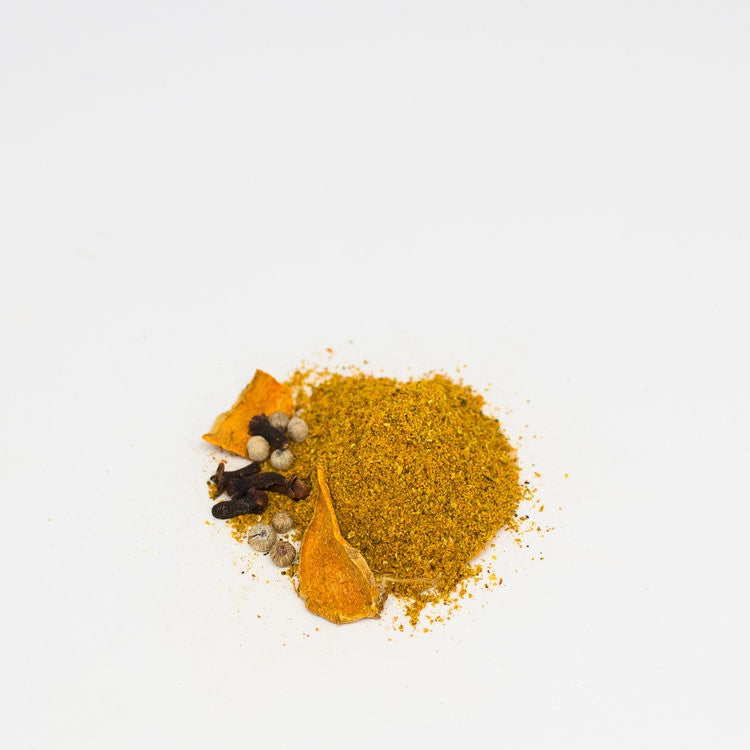 a small mound of the comfort curry spice blend alongside the whole spices that are in the blend