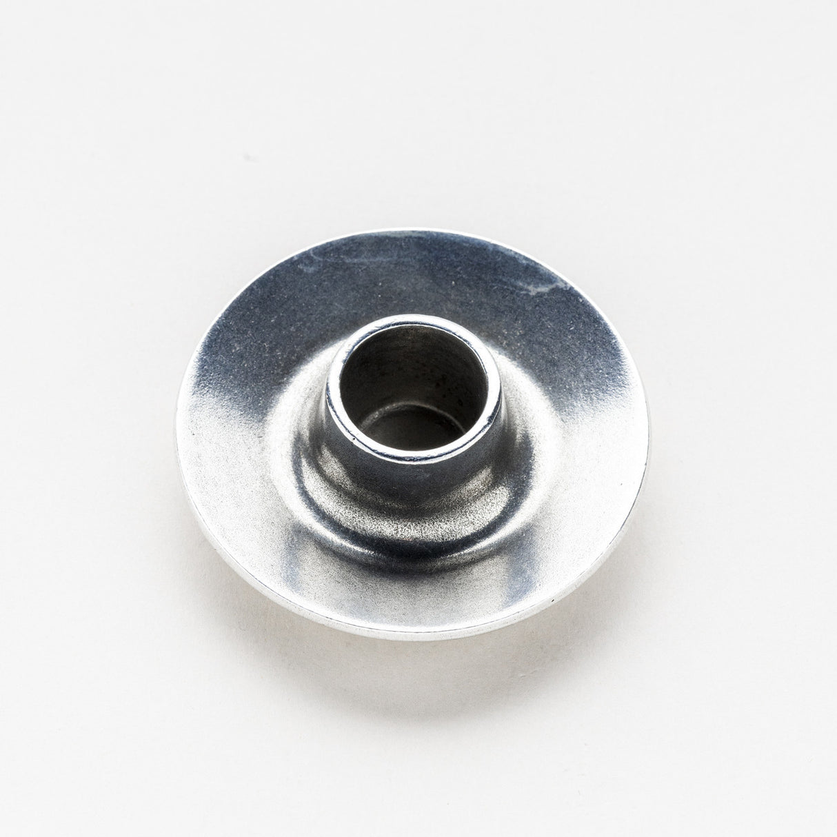 a simple, circular pewter candle holder against a white background