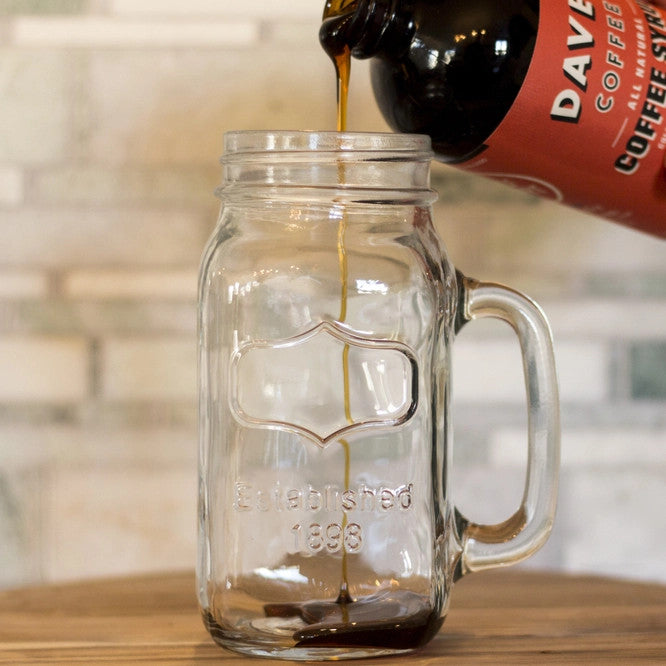 Dave's coffee syrup being poured into a glass mason jar mug