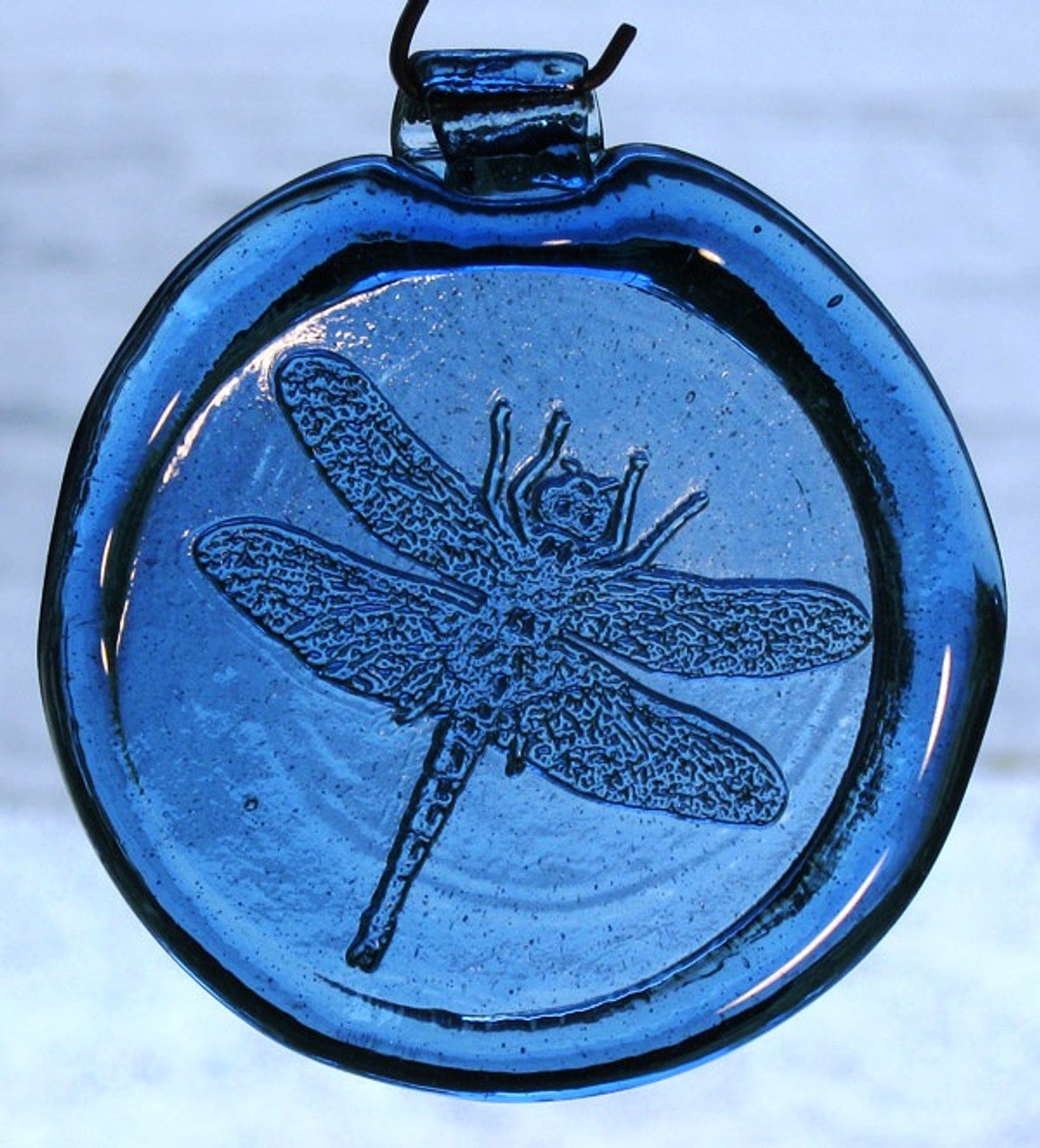 a blue, round glass suncatcher with a relief image of a dragonfly
