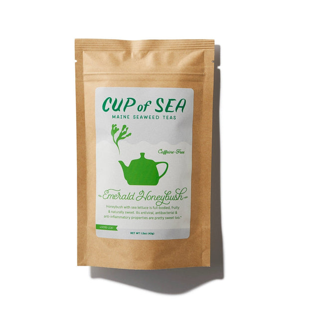 a kraft tea package with a white and green label that reads "Cup of Sea - Maine Seaweed Teas - Emerald Honeybush" with a graphic of a solid green tea kettle with seaweed shaped steam rising out of the spout