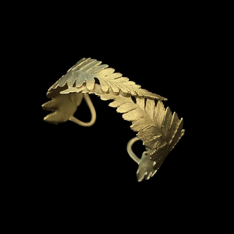 a metal fern cuff that is bronze cast from real ferns with a green patina