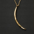 a slender gold pendant in the shape of a slice of the moon in its gibbous phase with 3 mini CZ stones on the bottom curve