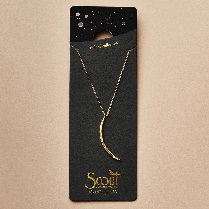 a slender gold pendant in the shape of a slice of the moon in its gibbous phase with 3 mini CZ stones on the bottom curve on a black card that serves as its packaging and shows more of the chain length