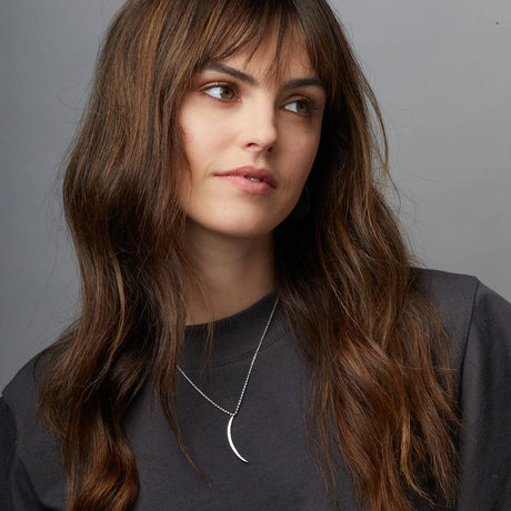 the silver gibbous slice necklace on a model showing that the chain length falls just below the collarbone