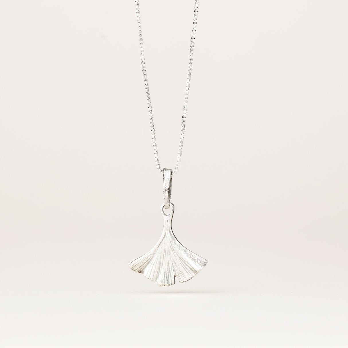 the back of the intricately detailed pewter ginkgo leaf shaped pendant hanging from a silver chain