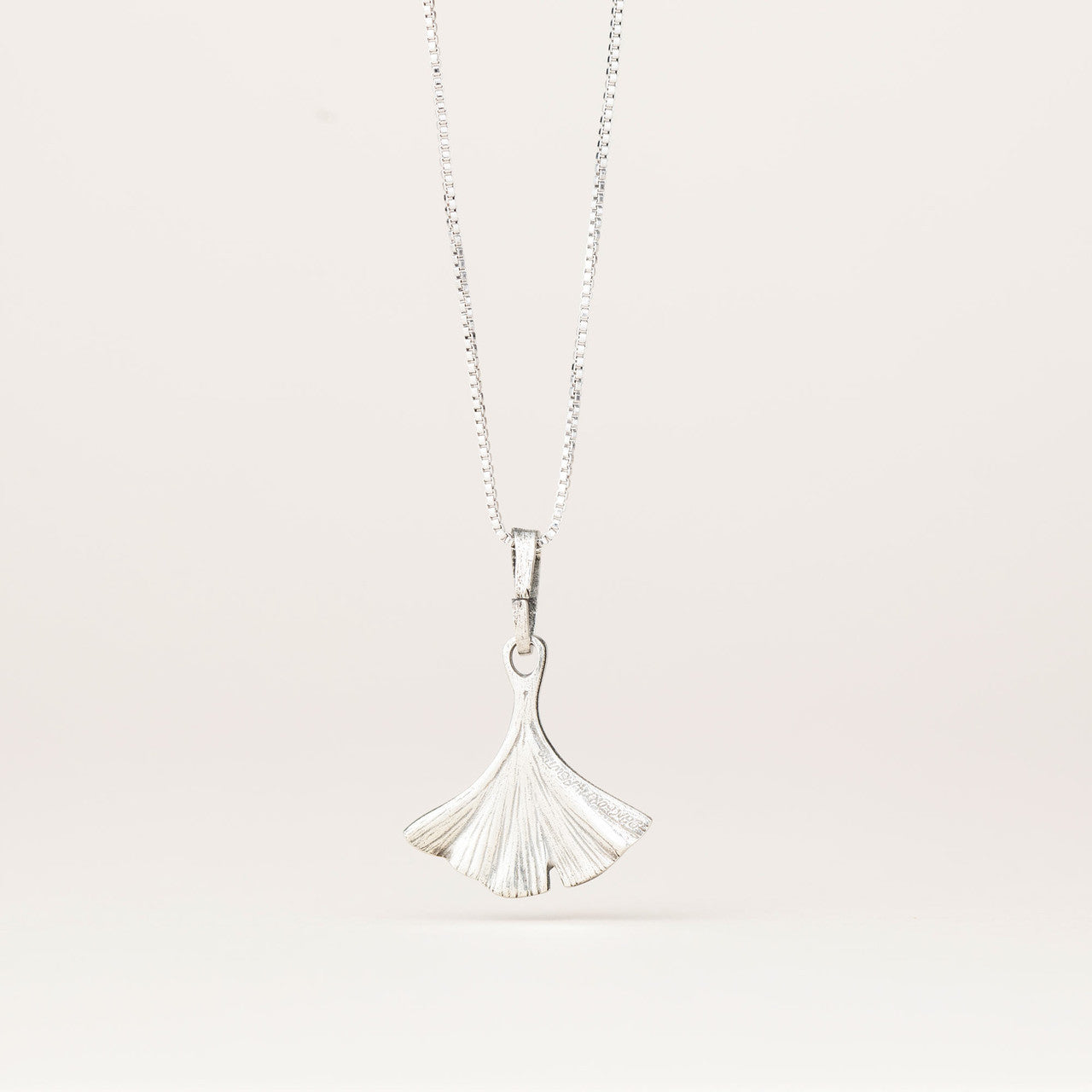 the back of the intricately detailed pewter ginkgo leaf shaped pendant hanging from a silver chain