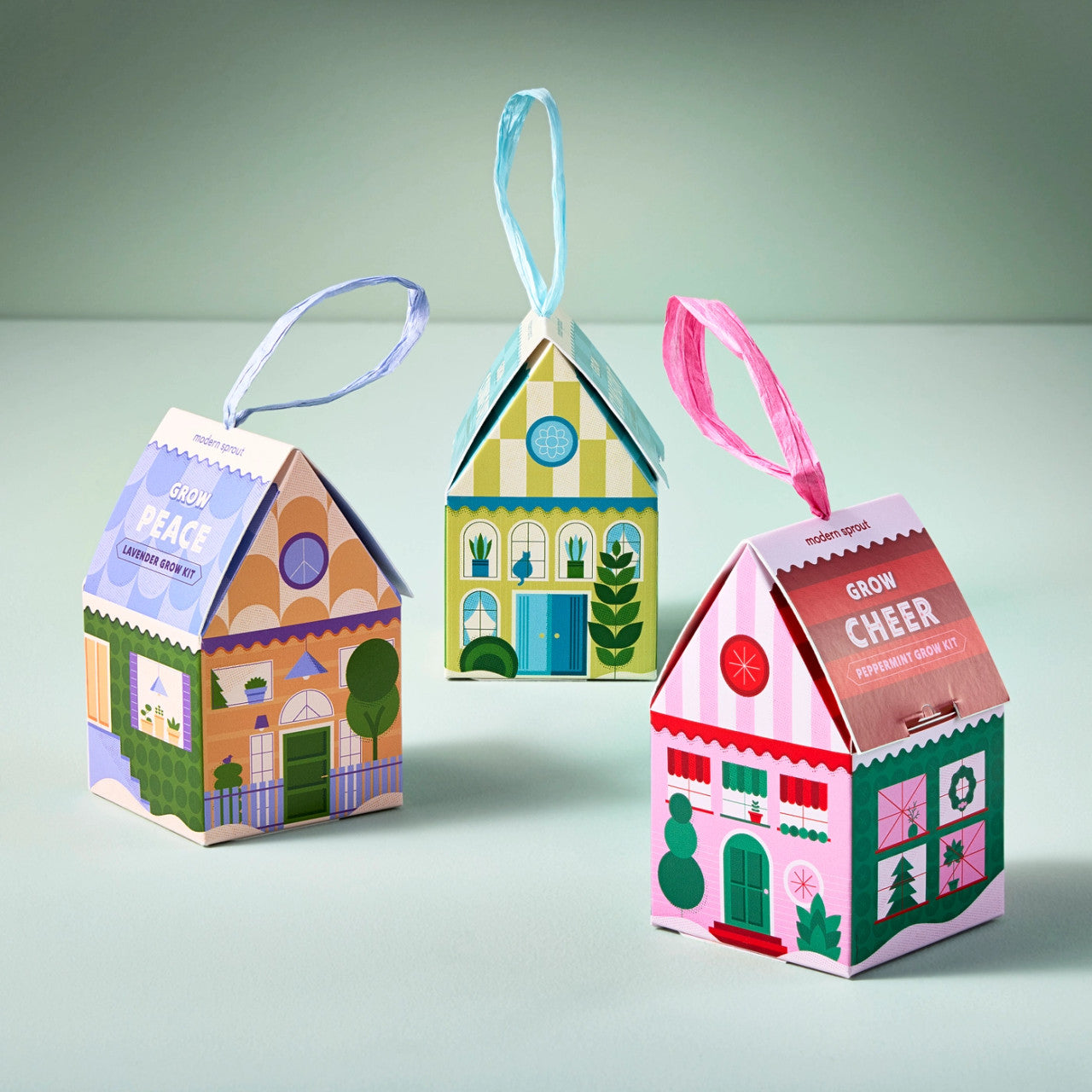 a trio of colorful house shaped ornaments with satin ribbons to hang on a tree
