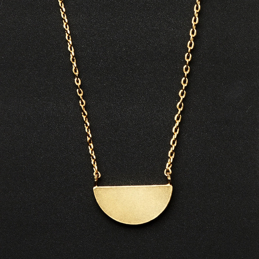 A gold necklace with a half moon pendant