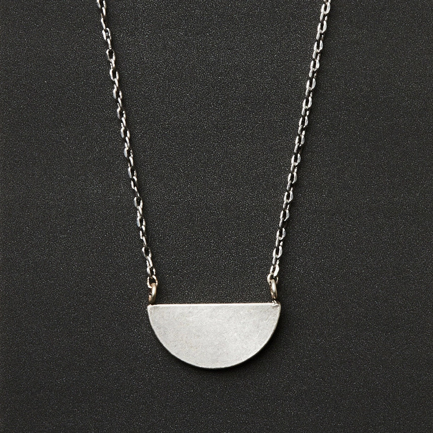 A silver necklace with a half moon pendant