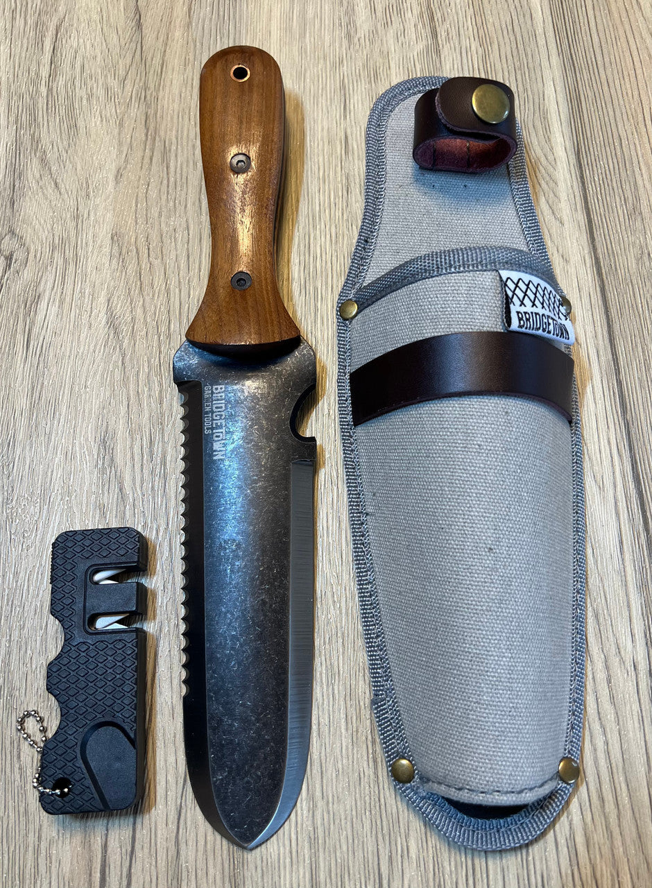 Essential Hori Hori knife shown side by side with its sheath and sharpener - side one of knife