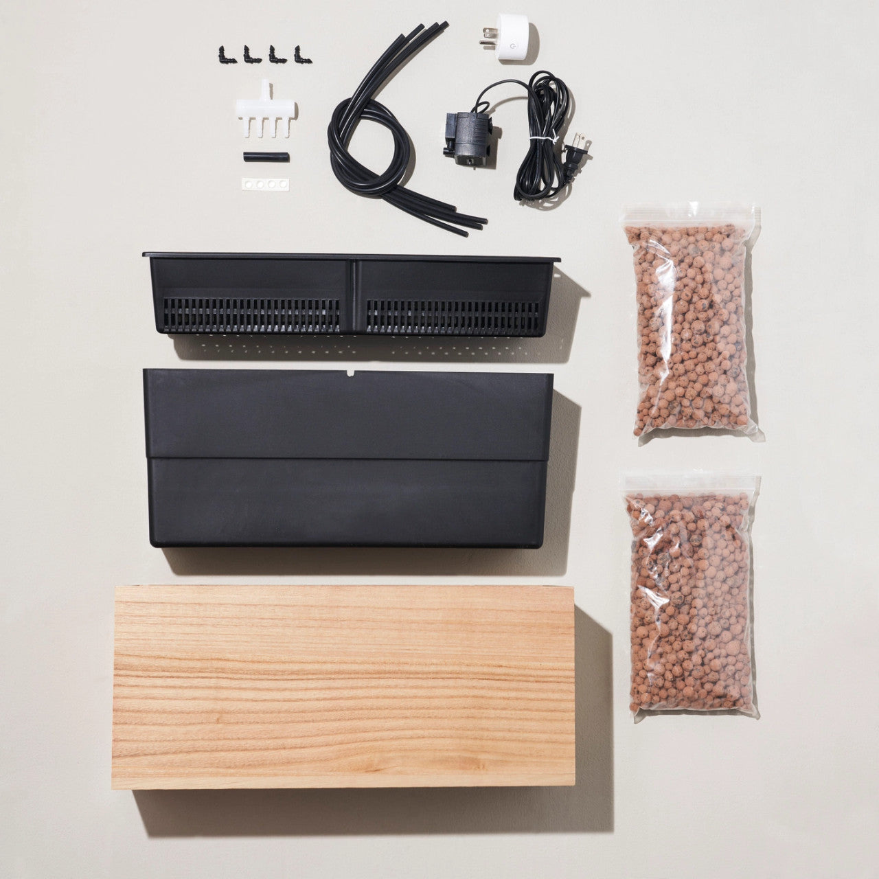 the contents of the box including bamboo box, nesting liners, pump with water level sensor, smart plug, four irrigation tubes, splitter, grow medium