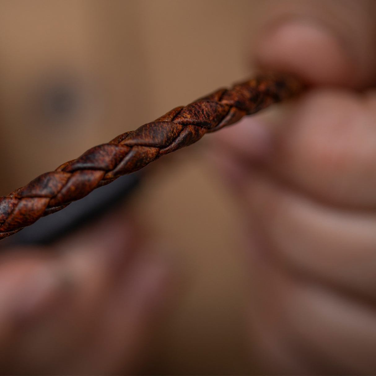 a close up of the braided detail of the moose leather bracelet that is held in a model's hands