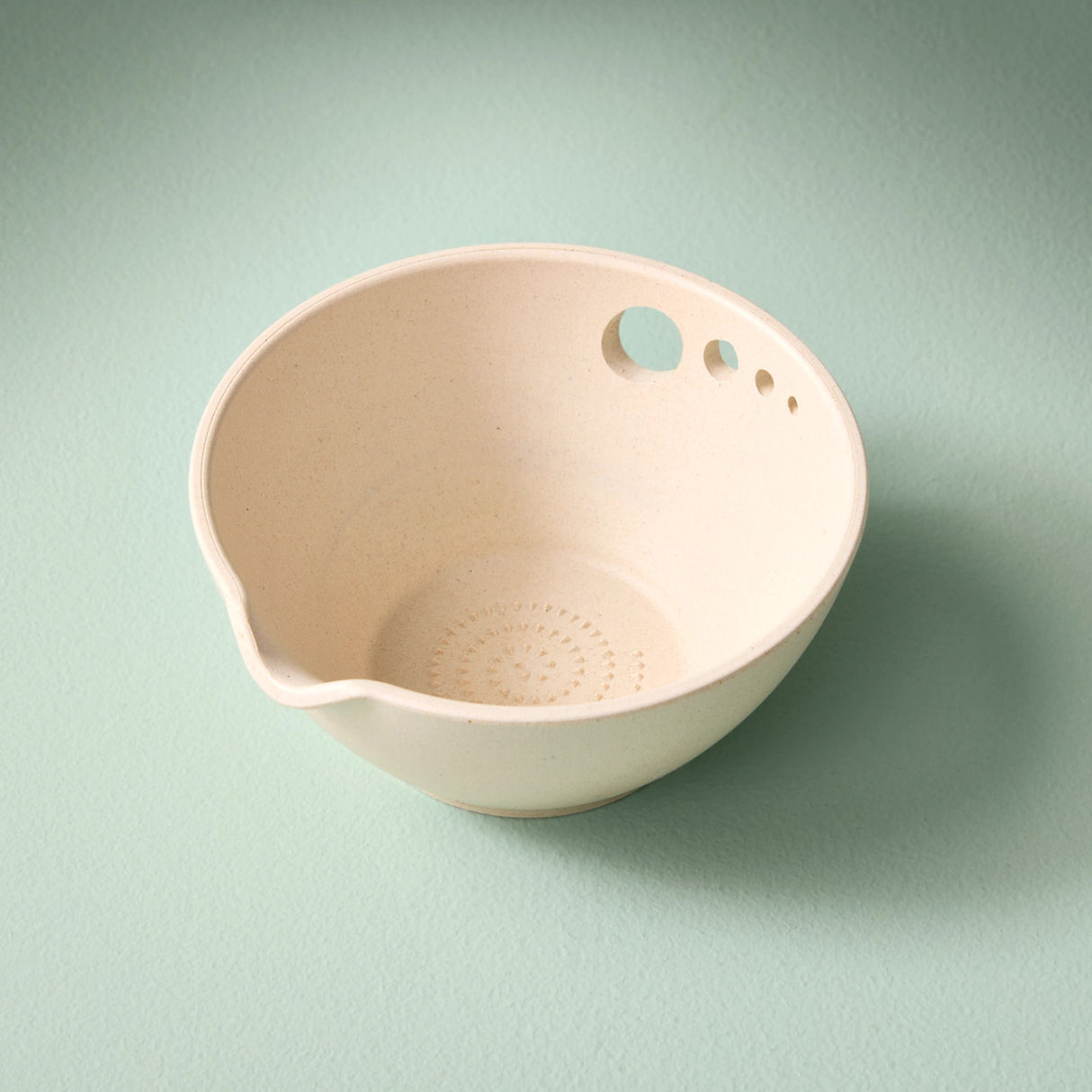 the peel grate & prep dish on its own showing the multiple holes for stripping herbs, the textured bottom for grating, and the pouring spout