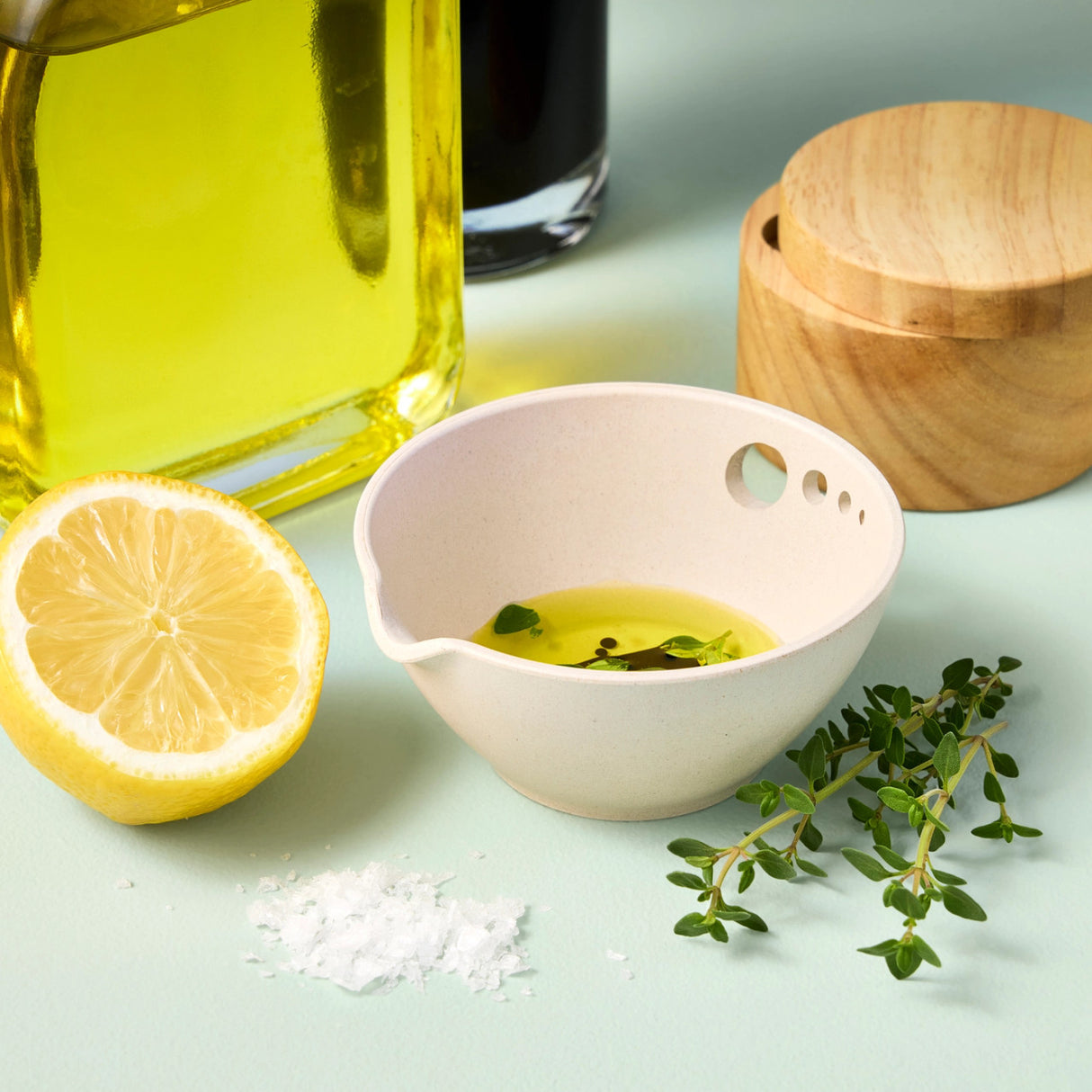 the peel grate & prep dish on a kitchen countertop with some olive oil, fresh herbs, salt, and a lemon