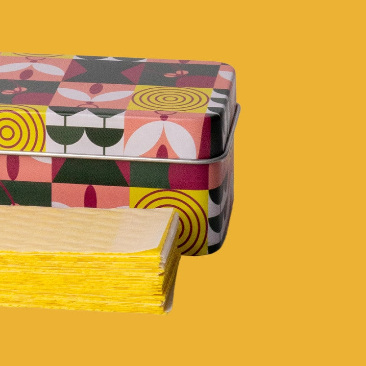 a side view of the pest traps in a neat stack in front of the container tin against a yellow background