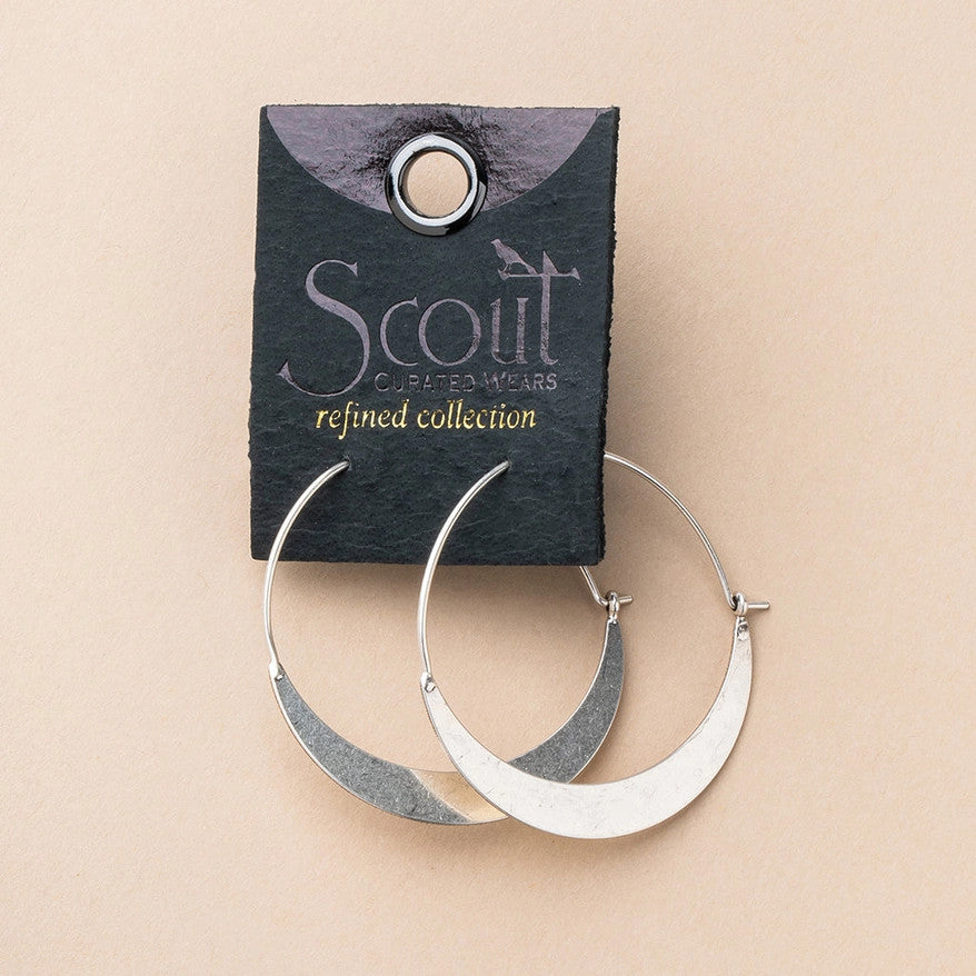 a pair of silver hoop earrings that take the shape of a crescent moon affixed to a black leather card with gold foil lettering