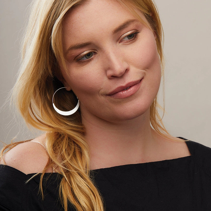 a model wearing the silver crescent hoop earrings