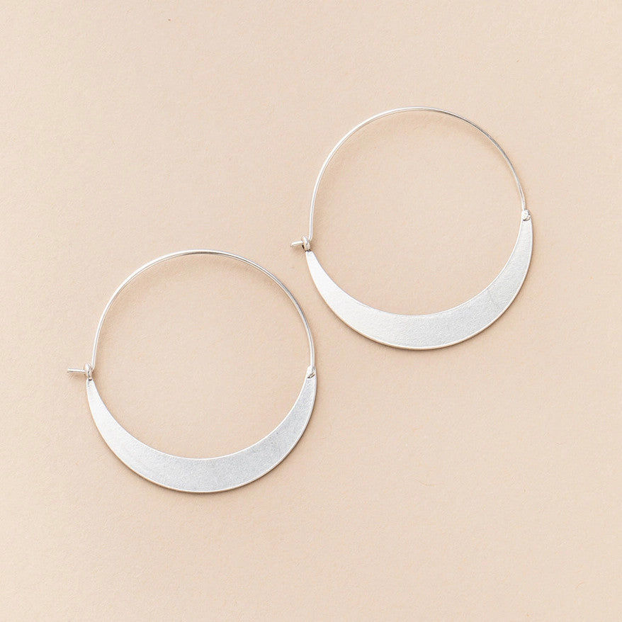 a pair of silver hoop earrings that take the shape of a crescent moon