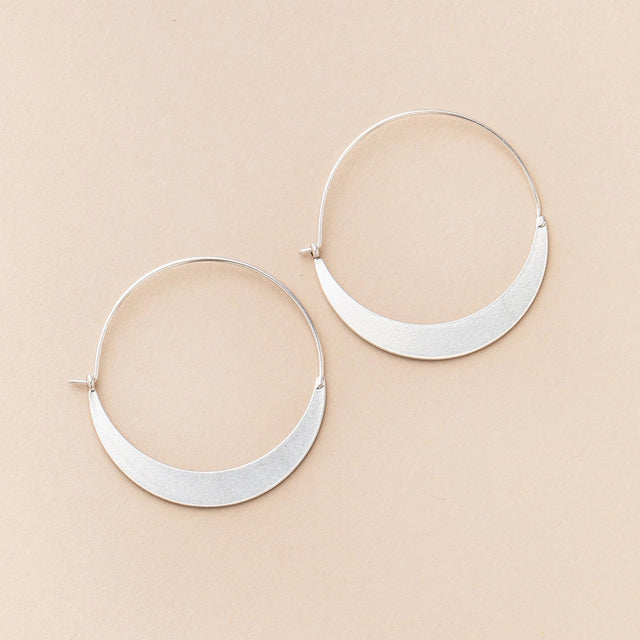 a pair of silver hoop earrings that take the shape of a crescent moon