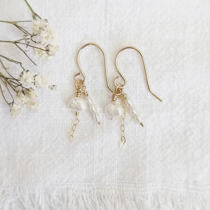 a pair of delicate gold earrings with tiny clusters of pearls dangling from a 14k gold chain