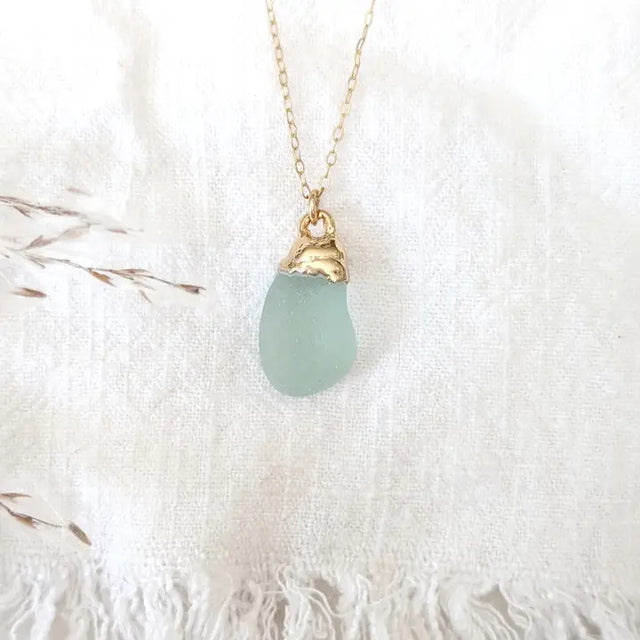 a delicate piece of aqua colored sea glass dipped in gold and suspended from a gold chain