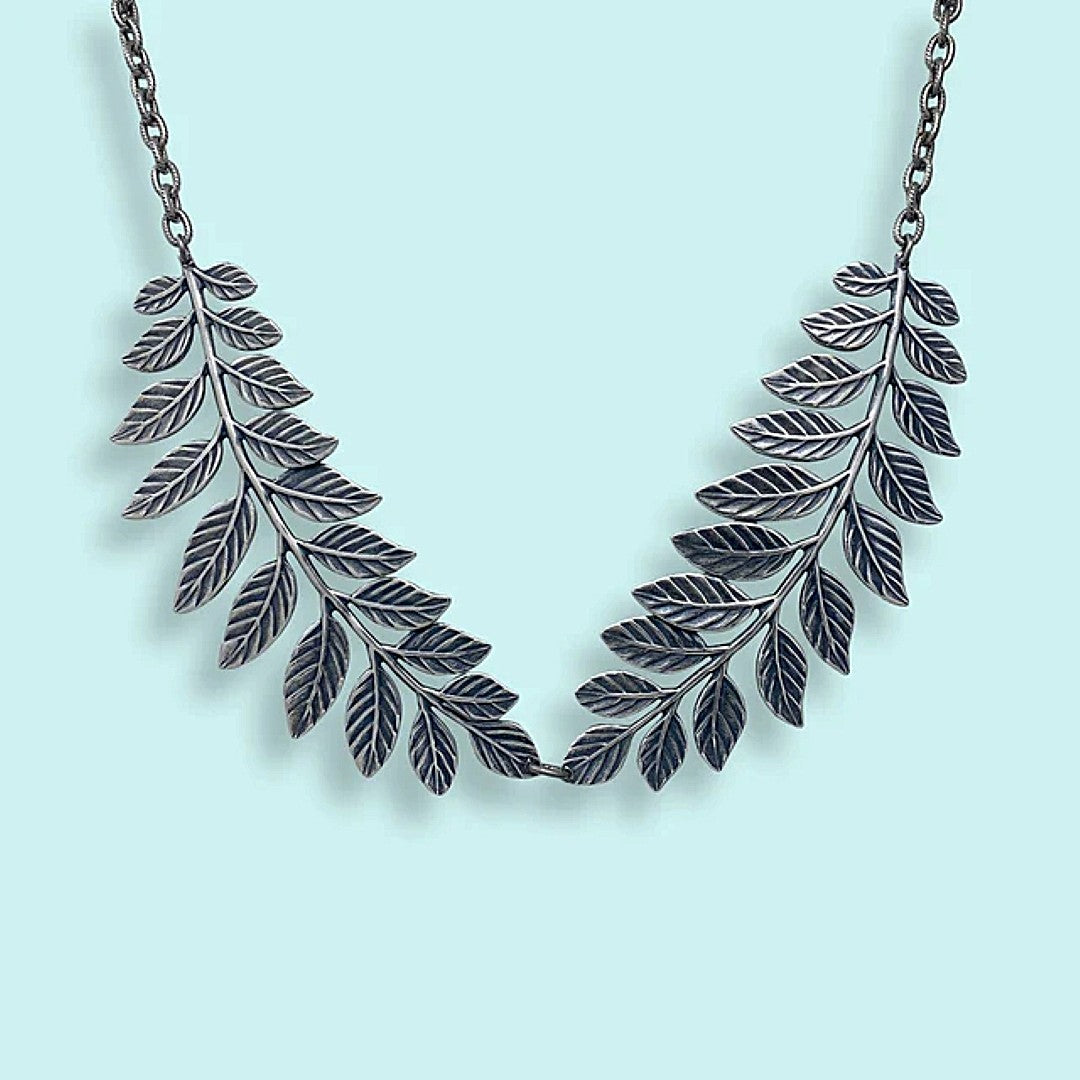 Silver leaf necklace on a light blue background