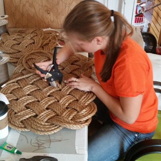 a weaver handcrafting a rectangular hand-woven nautical entry mat in manila rope