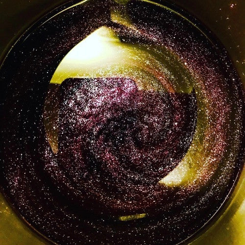 the Backyard Stargazing candle lit and seen from above to show how the wax shimmers when melted