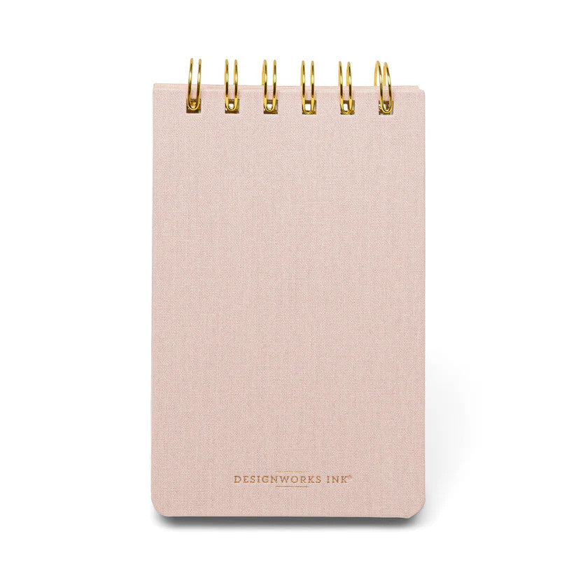 the back of the pale pink twin wire notebook showing the plain pink reverse cover with a small Designworks Ink logo in gold foil at the bottom of the notebook