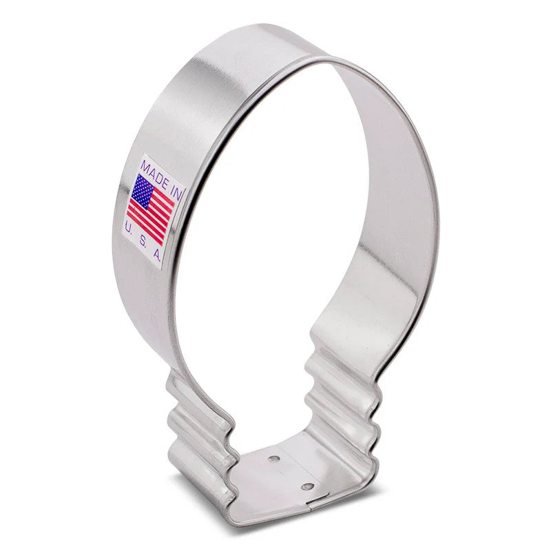 a silver, tin cookie cutter in the shape of a Christmas light bulb - oblong shape with a soft point at the top