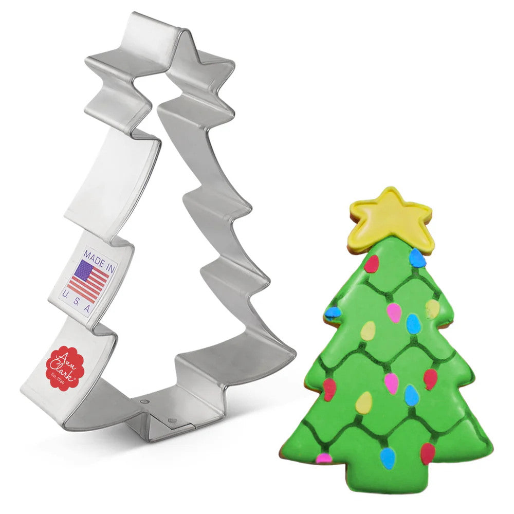 Tin cookie cutter in the shape of a Christmas tree with a star topper next to a fully decorated Christmas Tree with Star cookie complete with green icing and decorations