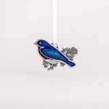 Decorative bluebird ornament with blue wings and silver body on a white background