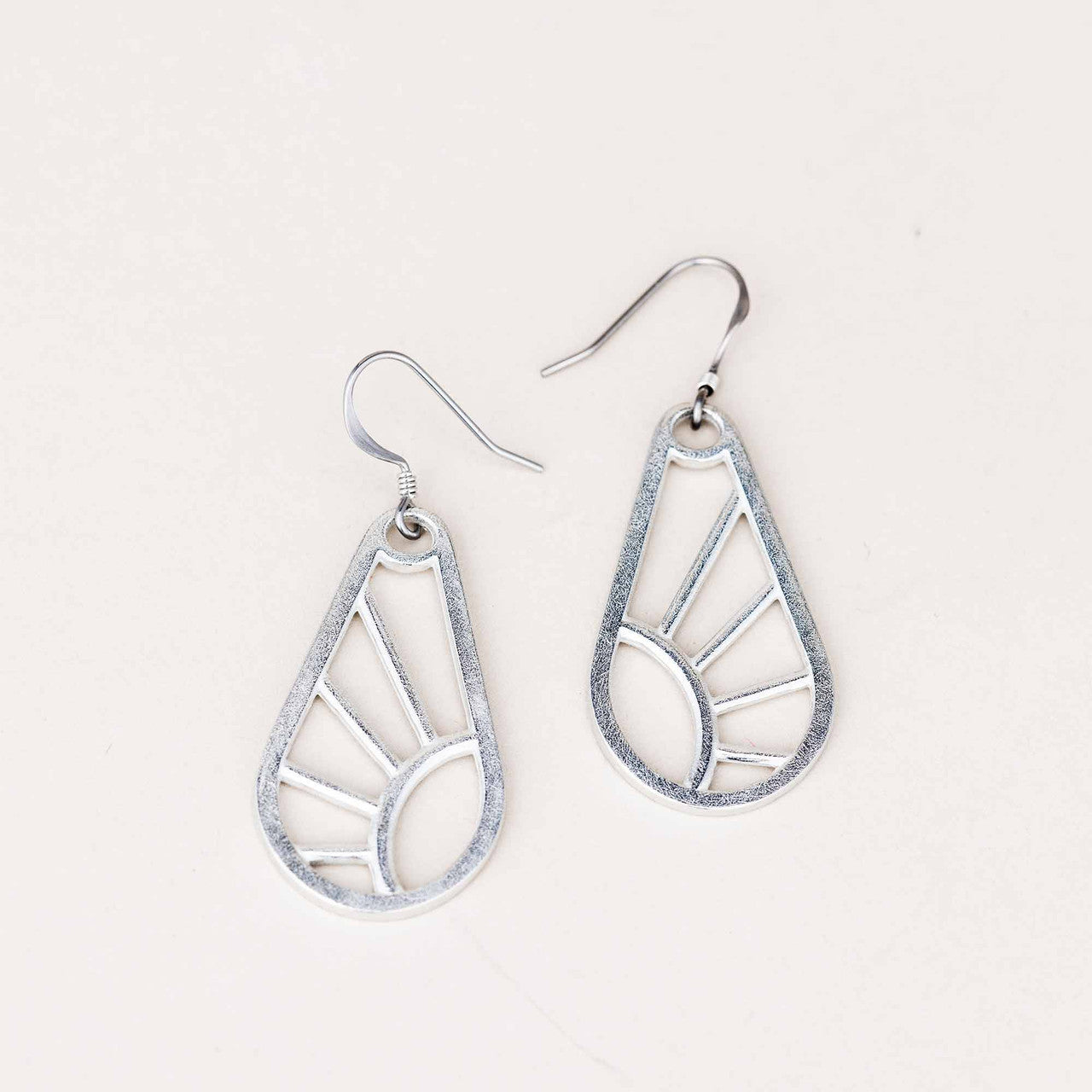 A pair of handcrafted Shine Wire Earrings on a white background, featuring an elegant geometric design inspired by sun rays. Made from pewter with surgical steel wires.