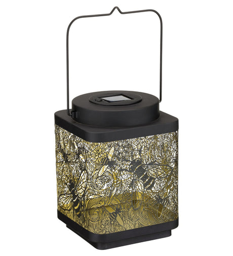 A cube shaped lantern with intricate design of bees in flight carved out of the sides of the lantern against a white background