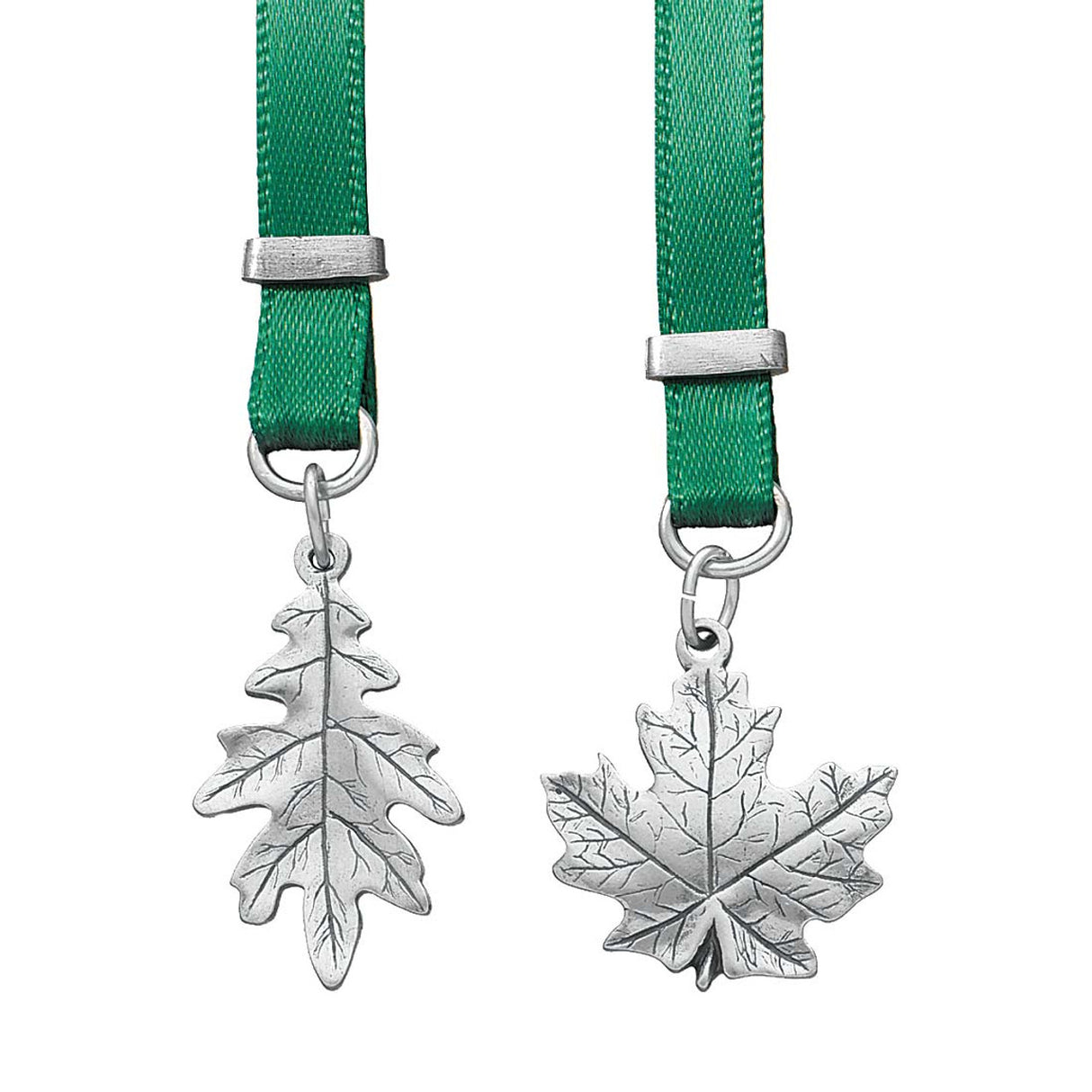 Two silver leaf pendants on green ribbons with silver clasps against a white background