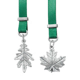 Two silver leaf pendants on green ribbons with silver clasps against a white background