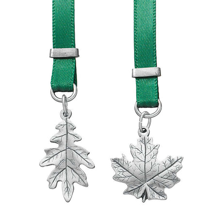 Two silver leaf pendants on green ribbons with silver clasps against a white background