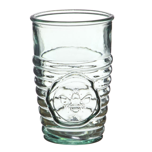 a clear drinking glass with ribbed texture on the lower half with a circular emblem of a bee