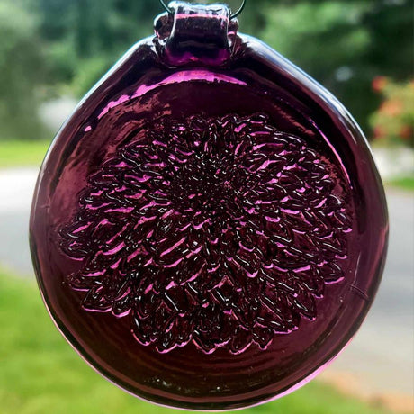 Purple glass ornament with textured surface against a blurred background