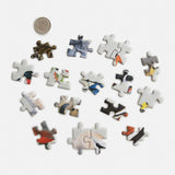 Set of puzzle pieces with bird illustrations next to a dime for scale on a white background