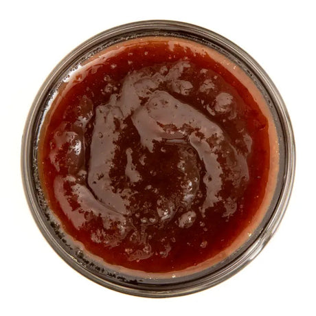 above view of an open jar of the Heirloom Apple with Maple Syrup butter showing the rich red color of the butter
