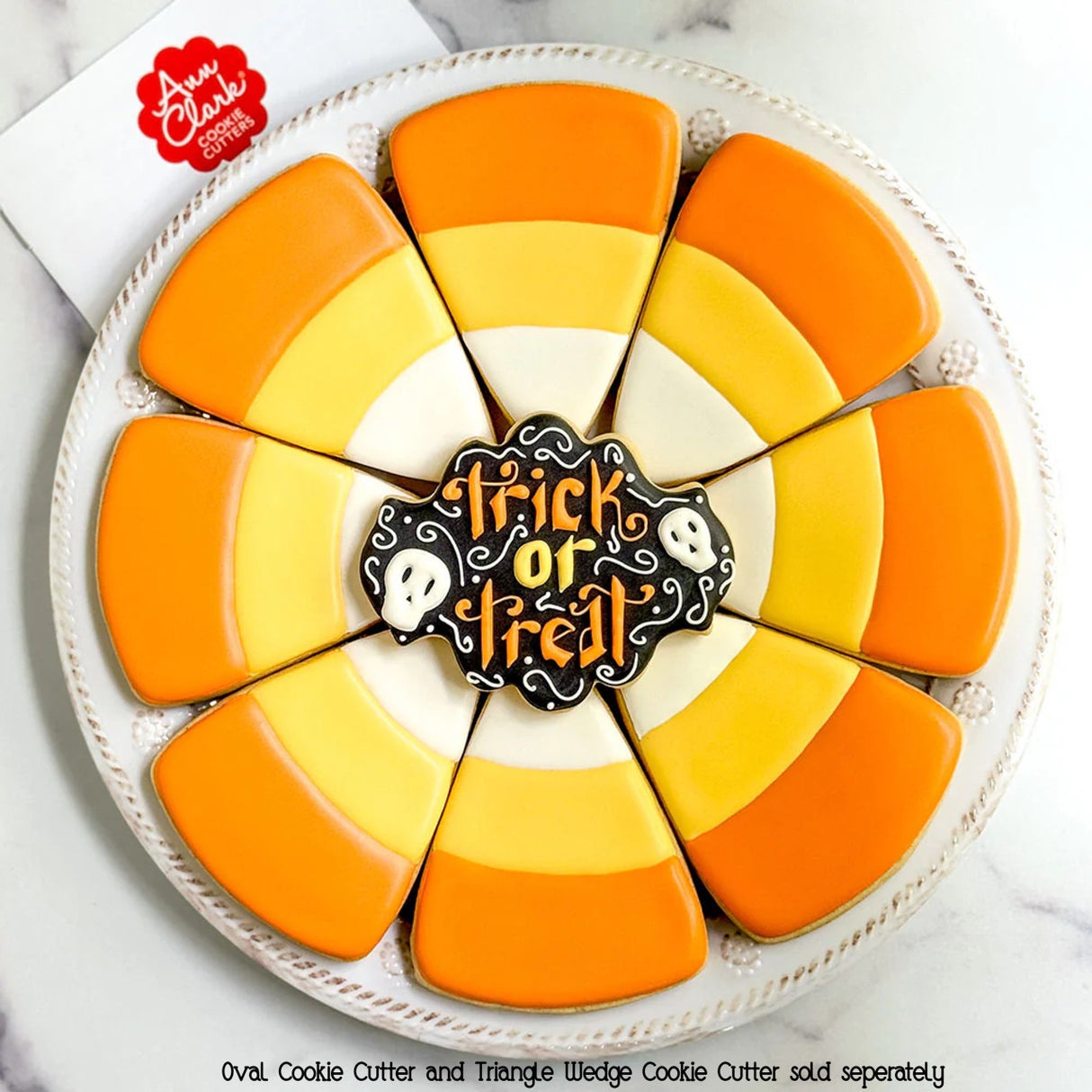 A circular decorative cookie centerpiece made up of wedge-shaped cookies decorated like Candy corn with a stylish ornate oval center cookie that is decorated and says "Happy Halloween" showing the creative possibilities of this cookie cutter