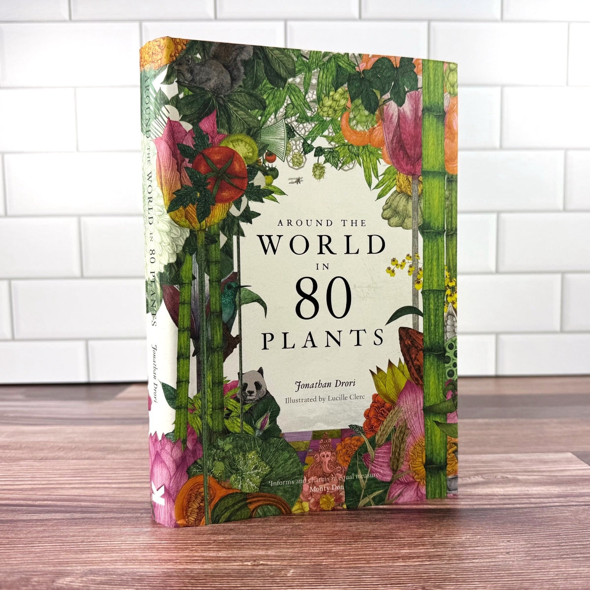 Book titled 'Around the World in 80 Plants' with colorful plant illustrations on a wooden surface.