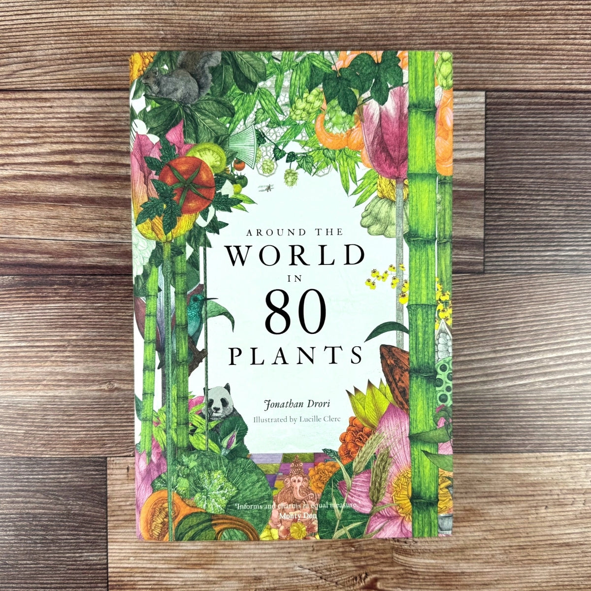 Book cover of 'Around the World in 80 Plants' on a wooden surface