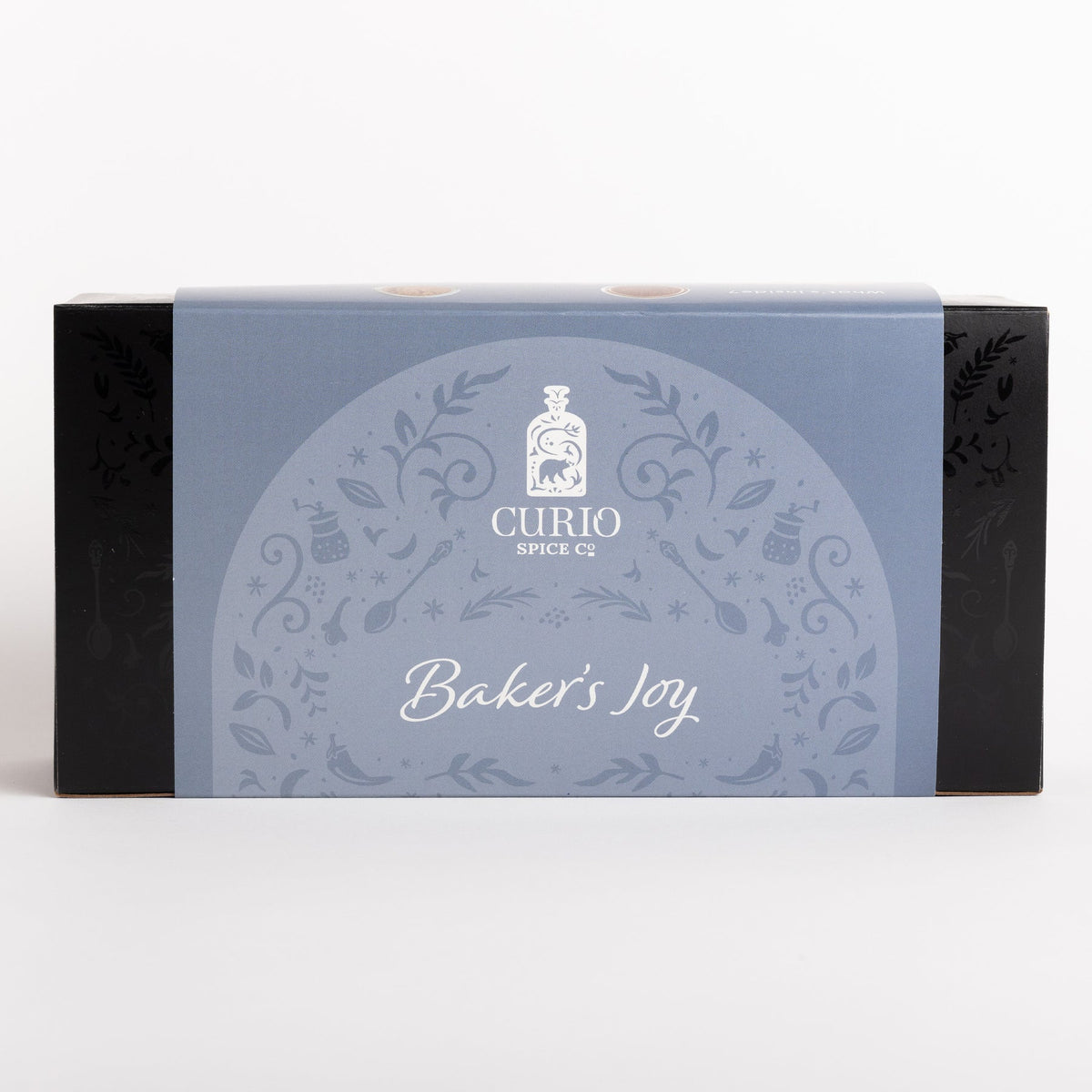 Curio Spice Co. 'Baker's Joy' spice box packaging, featuring a light blue central label with white decorative patterns and text, flanked by black sides, on a clean white background.